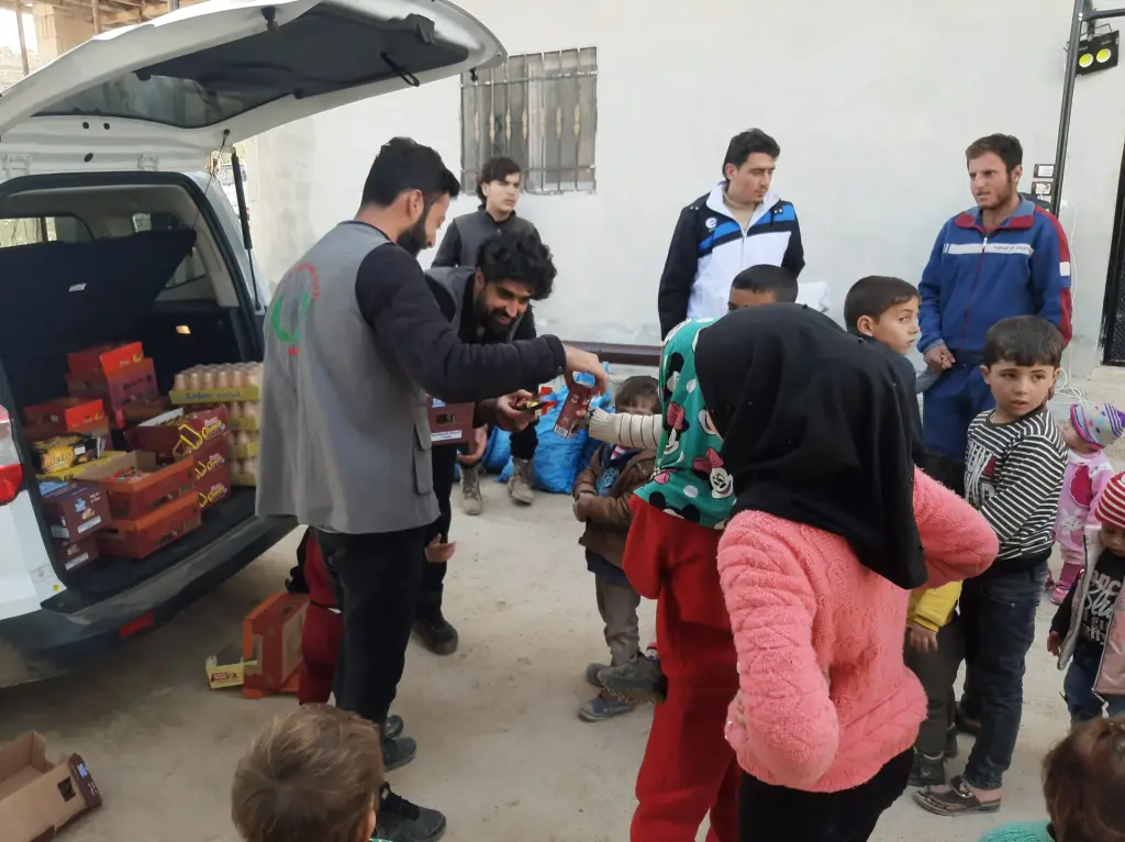 Gönüllüler araçtan çocuklara yardım dağıtıyor