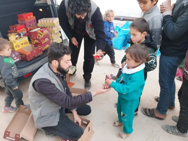 Diz çöken gönüllü küçük bir çocuğa hediye veriyor