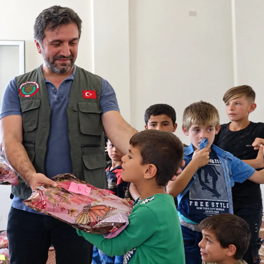 Gönüllü bir çocuğa kıyafet hediye ediyor